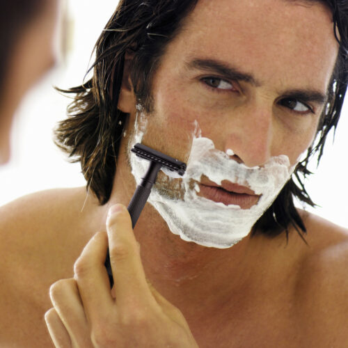 Man shaving face in mirror