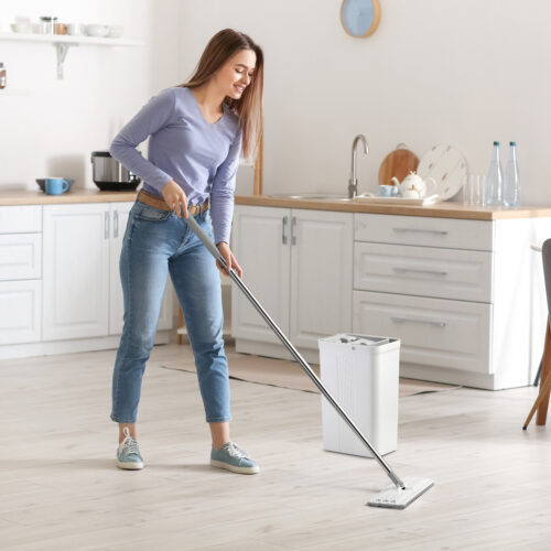 Young woman mopping floor in kitchen