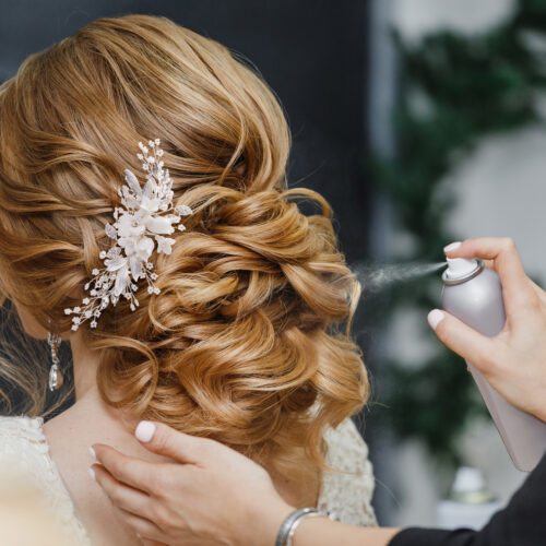 Master stylist makes the bride wedding hairstyle using spray lacquer fixing