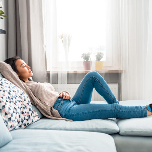 Relaxed smiling asian woman sitting on sofa at home