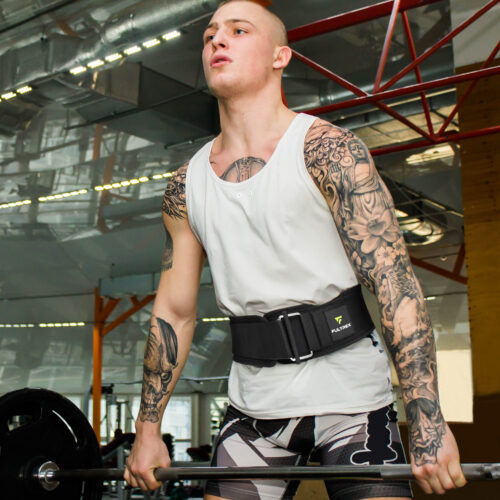 Young guy raises heavy barbell in the gym, deadlift process. Tattooed handsome sportsman in a gym. MMA training program. Lifestyle, healthy, sport. Weightlifting in a power lifting belt, powerlifting